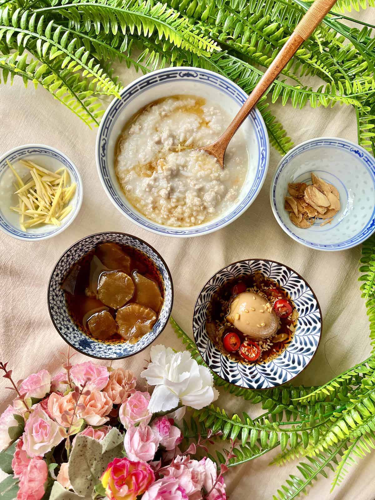 A bowl of pork and ginger congee with side dishes.