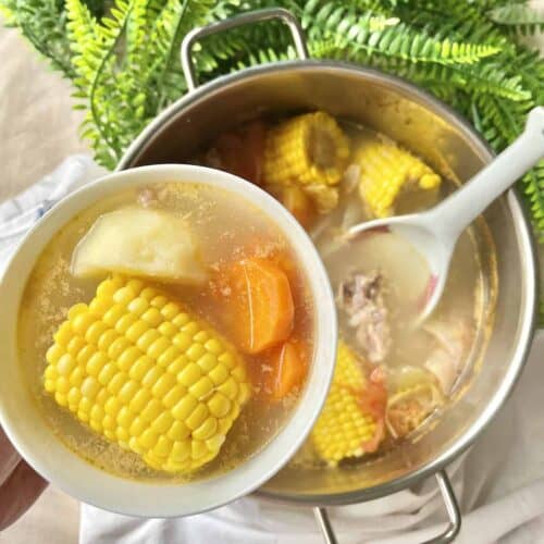 Close-up of a bowl of ABC soup with corn, potato, carrot and tomato.