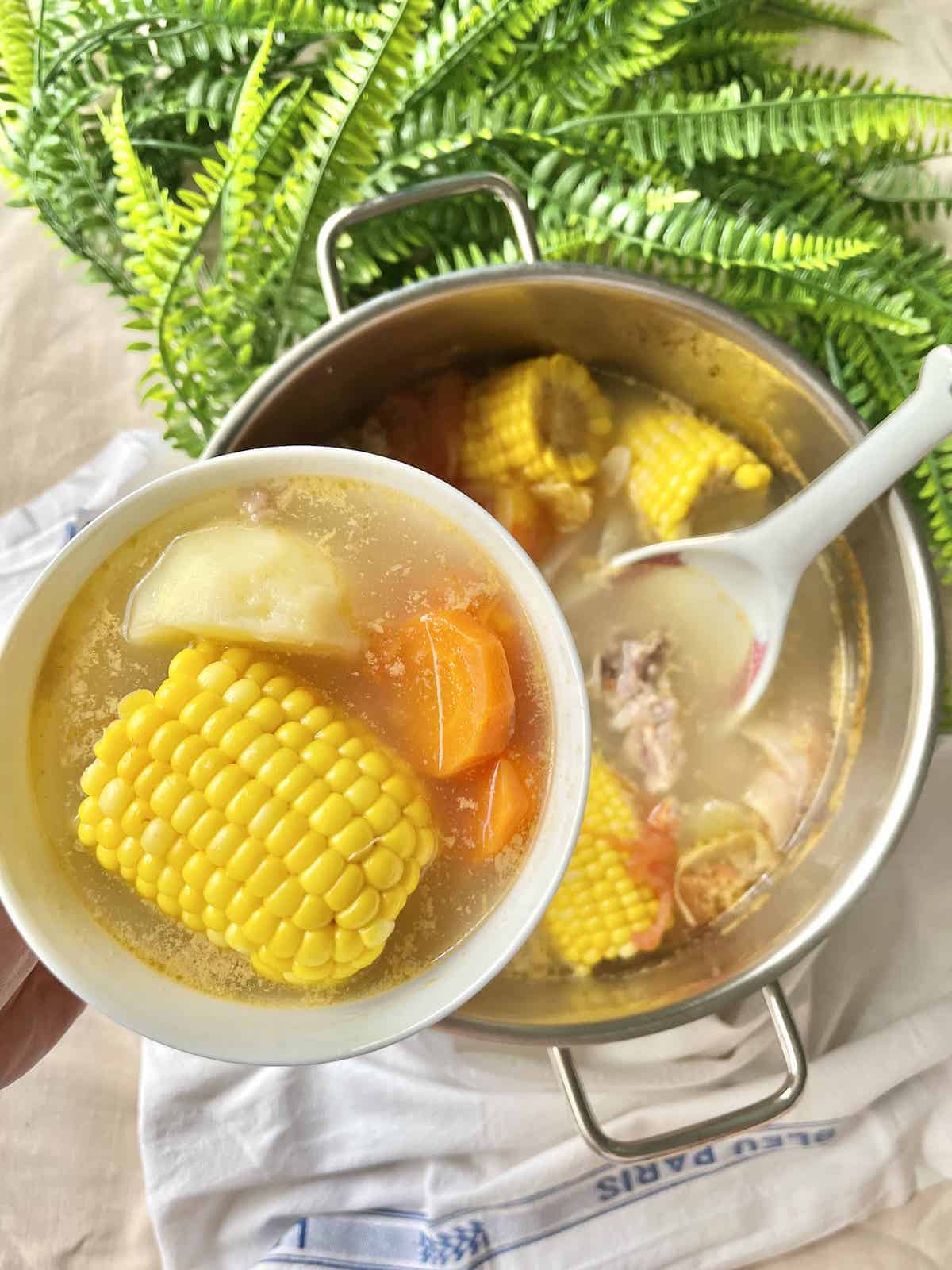 Close-up of a bowl of ABC soup with corn, potato, carrot and tomato.