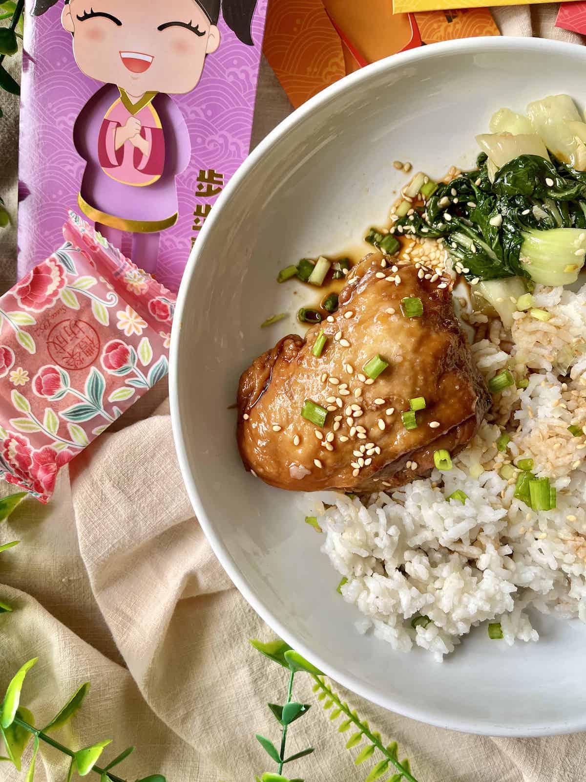 Chicken thigh with sesame seeds, green onions, green veggies and white rice.