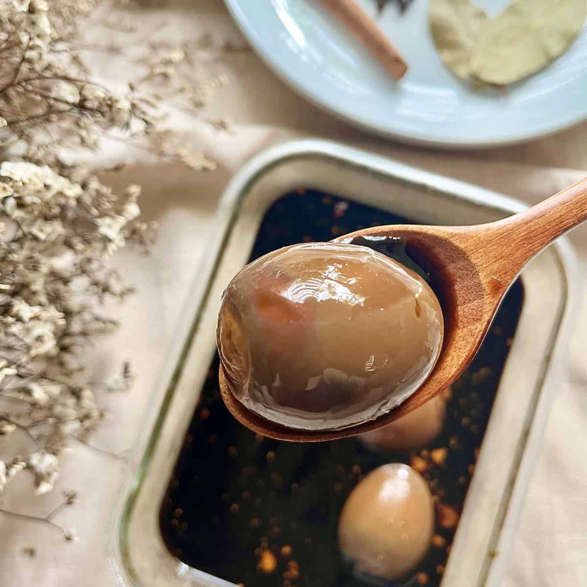 Close-up of a Chinese braised egg in a wooden spoon.
