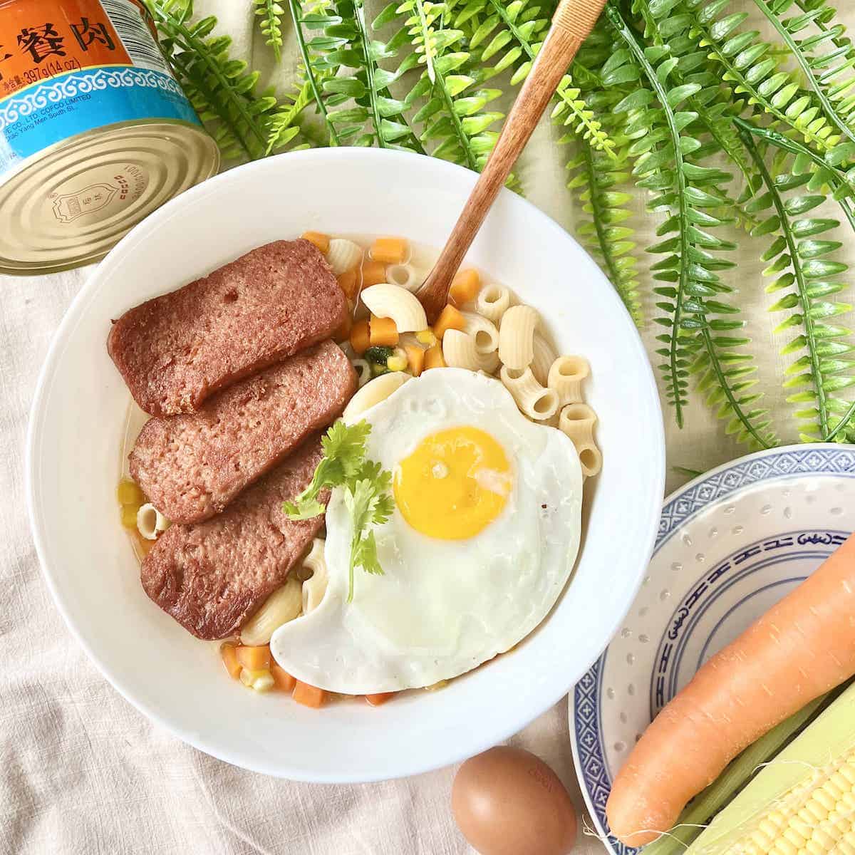 A bowl of Hong Kong chicken macaroni soup with a fried egg and SPAM.