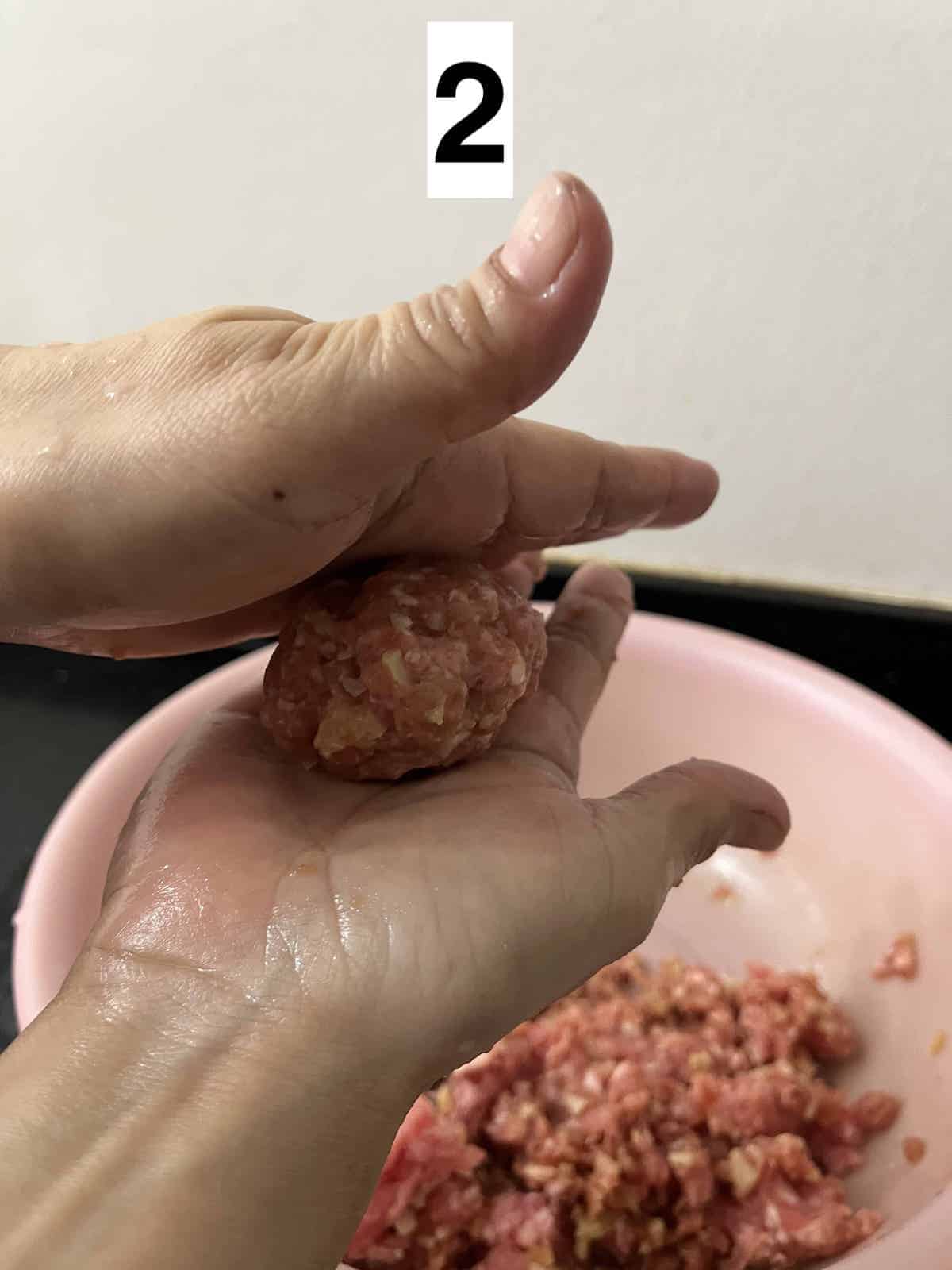 Rolling a ball of pork in between 2 hands.