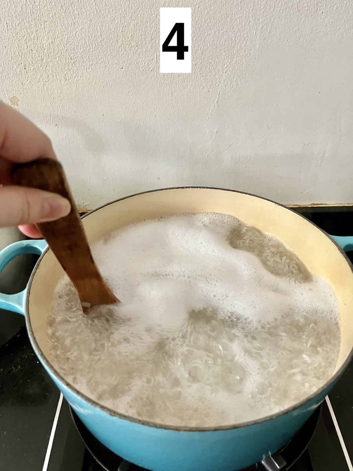 Stirring a boiling pot of rice and water.