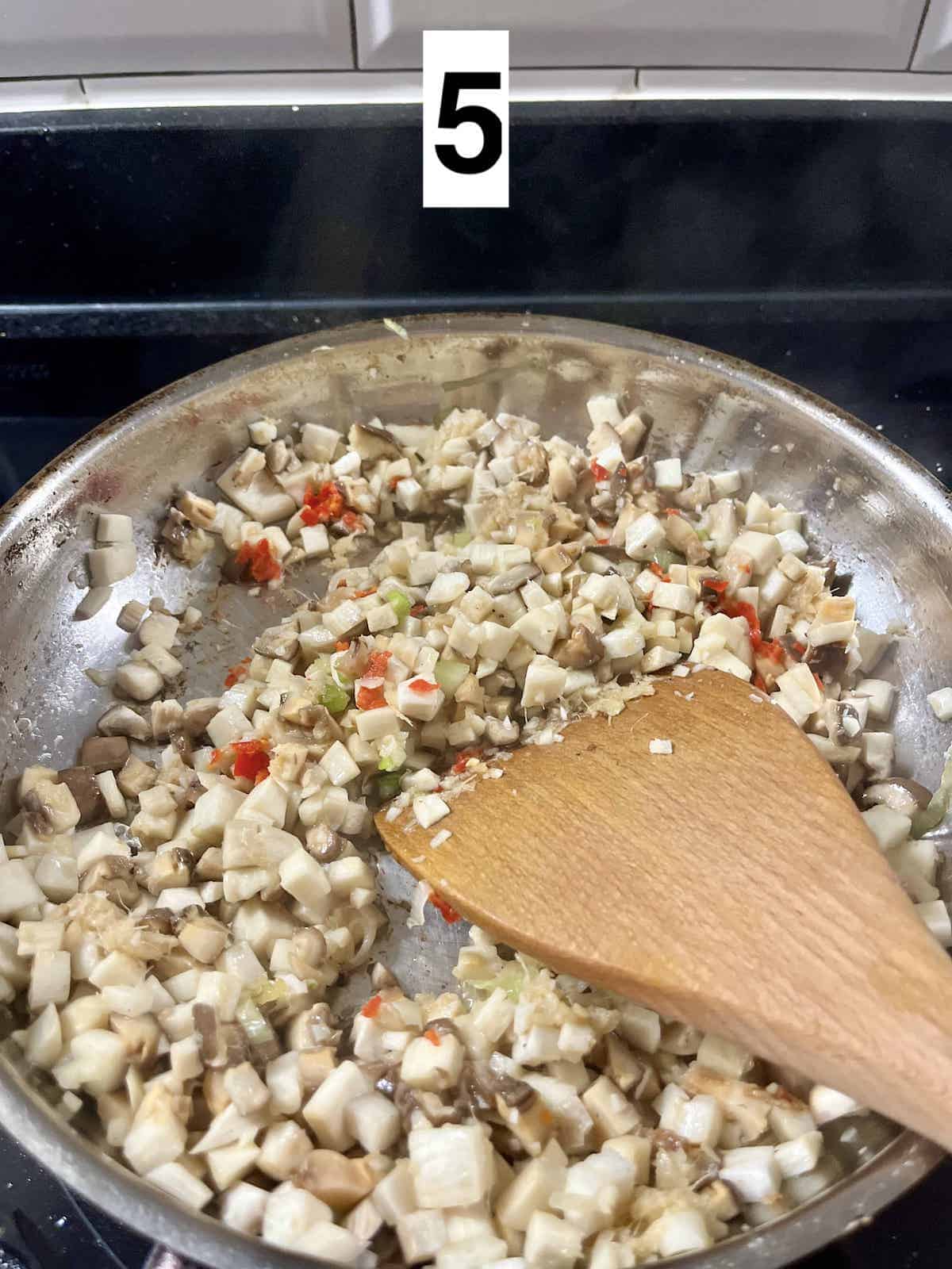 Stir frying diced mushrooms, chilies and spring onions in a pan.