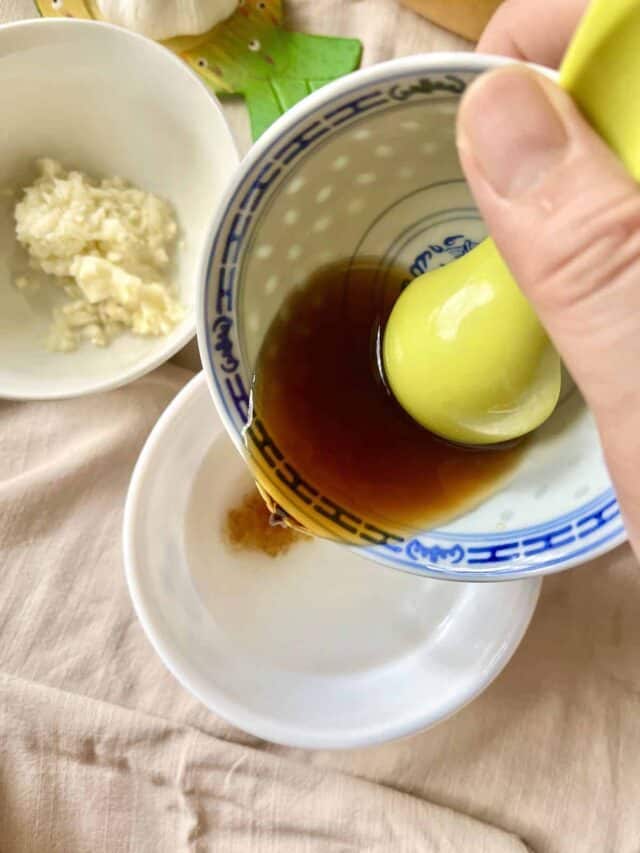 Pouring fish sauce into a. bowl of sugar and hot water.