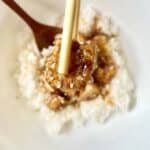 Close-up of a crispy tofu cube coated in white sesame seeds.