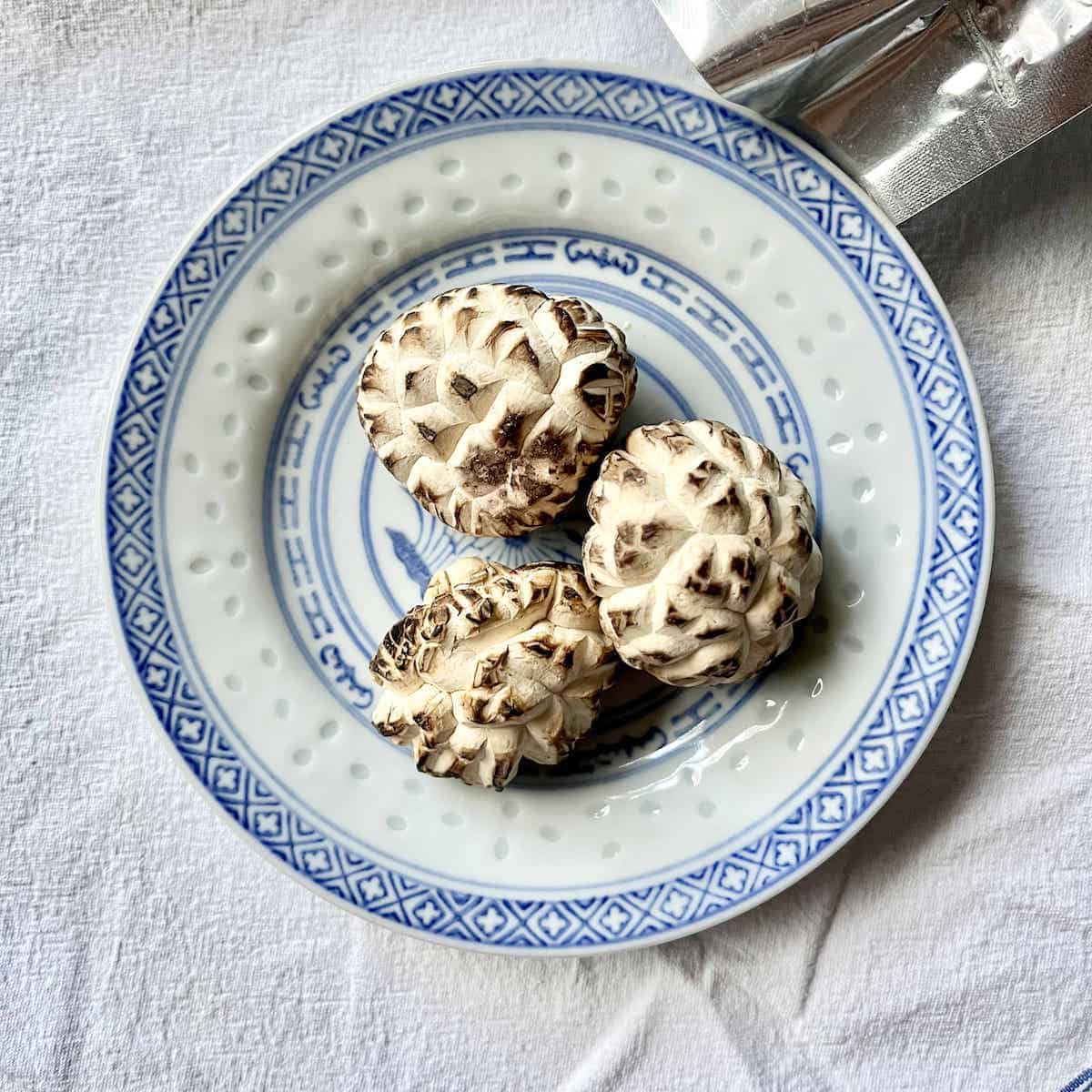 3 dried shiitake mushrooms on a plate, caps up.