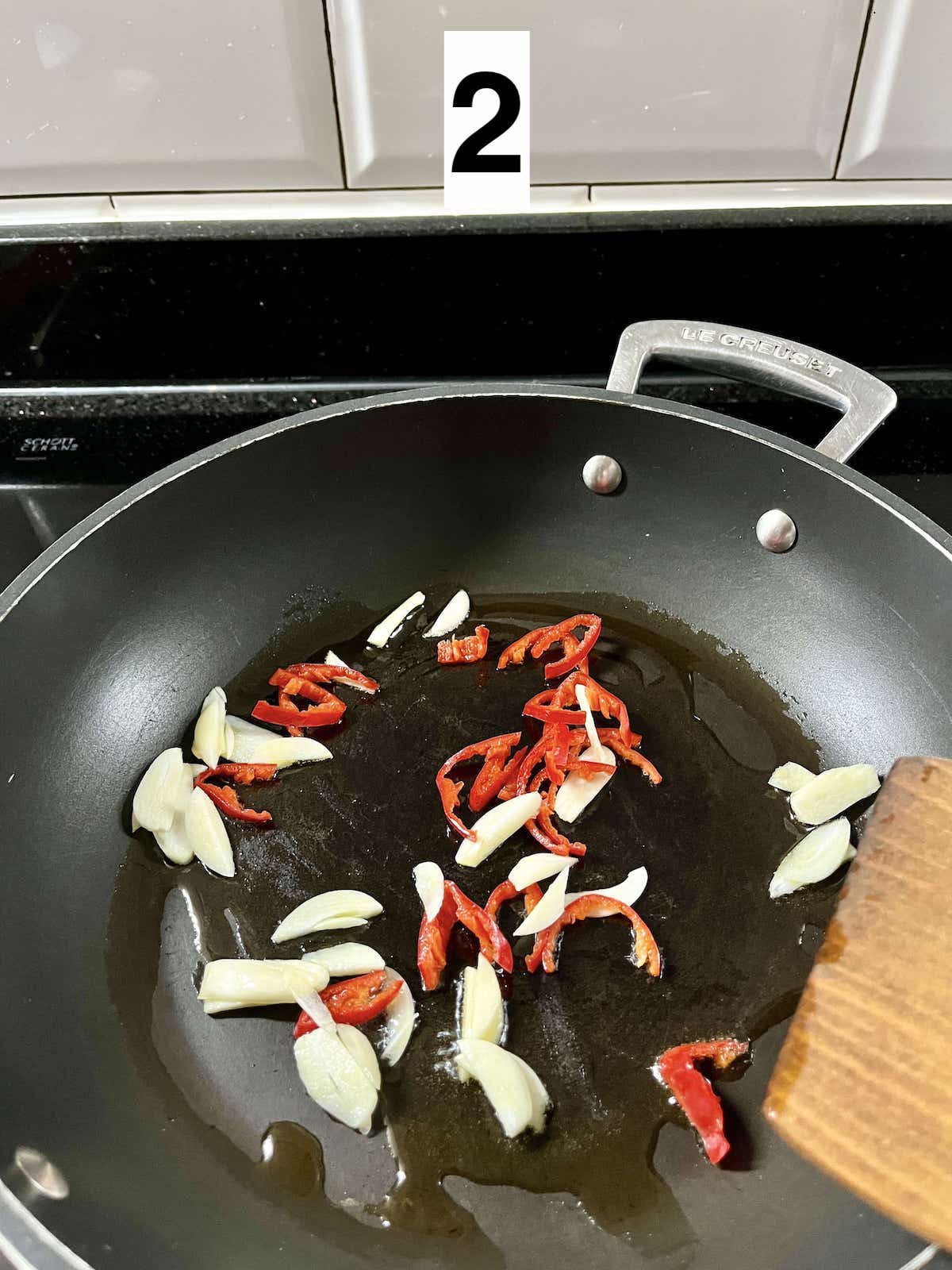 Stir-frying sliced garlic and red chilies.