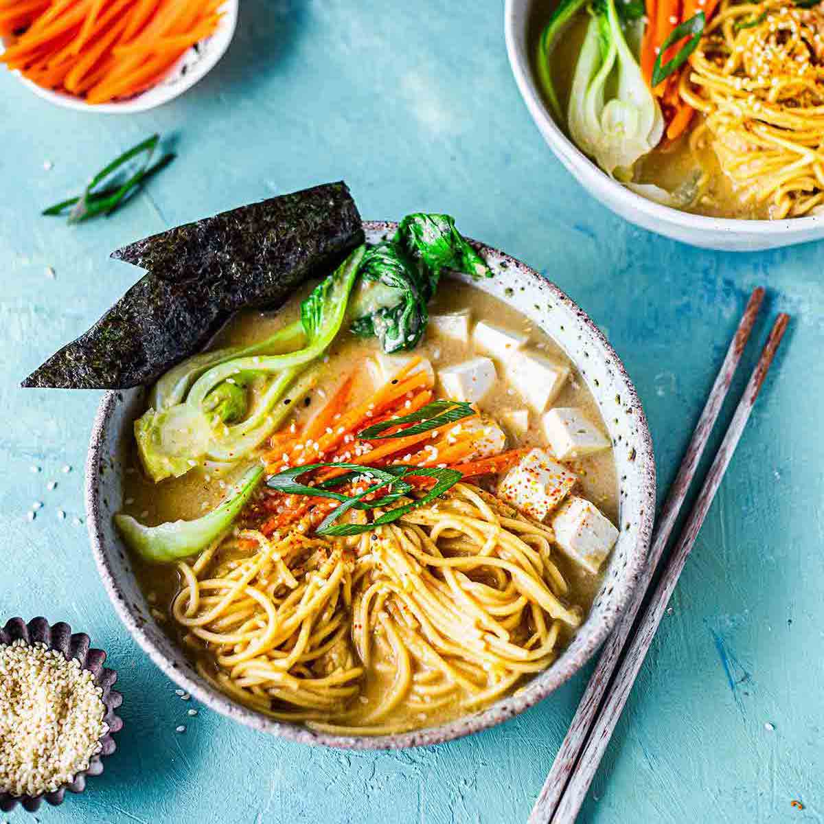 A bowl of Japanese soup noodles against a blue background.