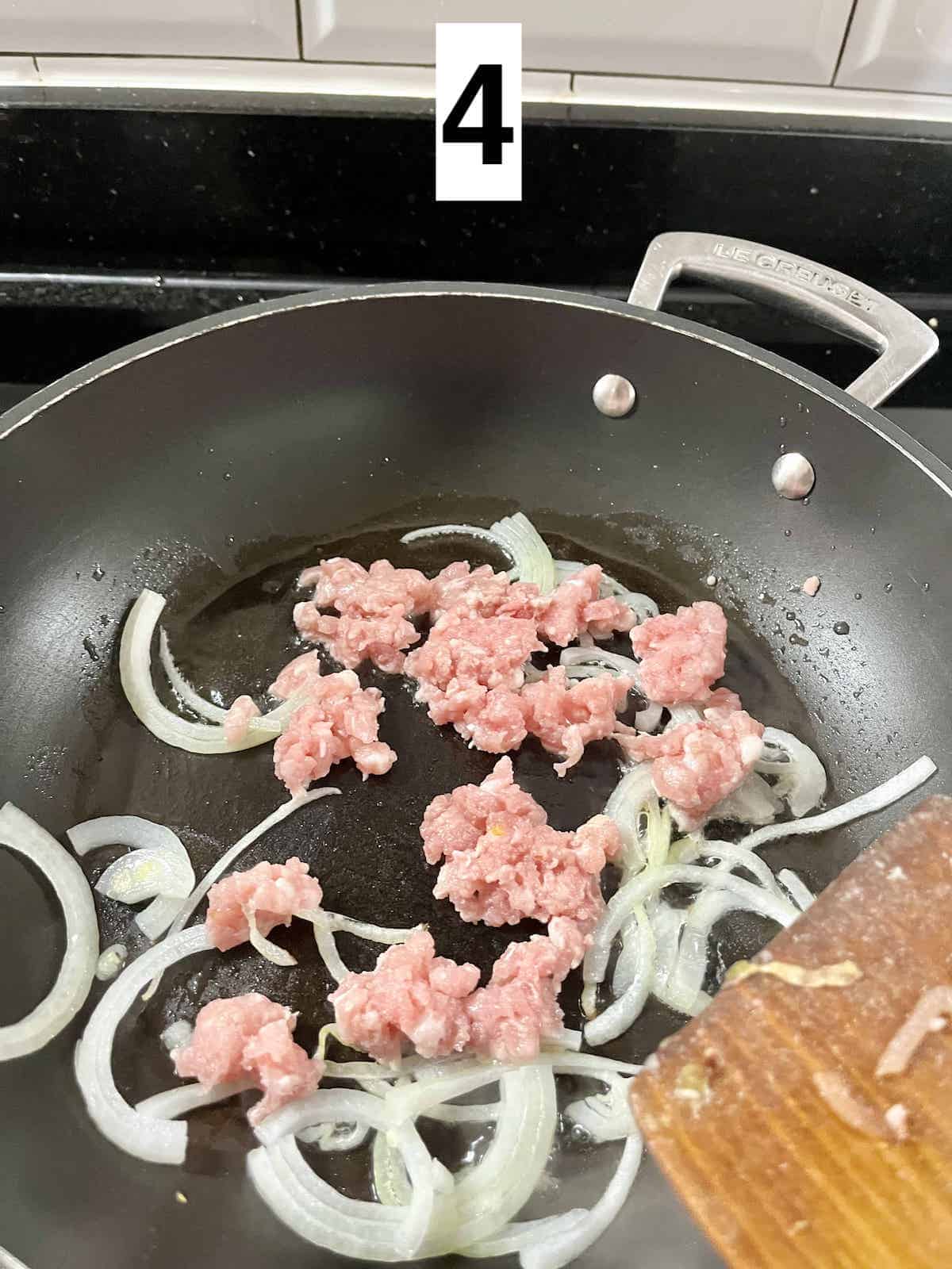 Stir-frying ground pork and onions in a hot pan.