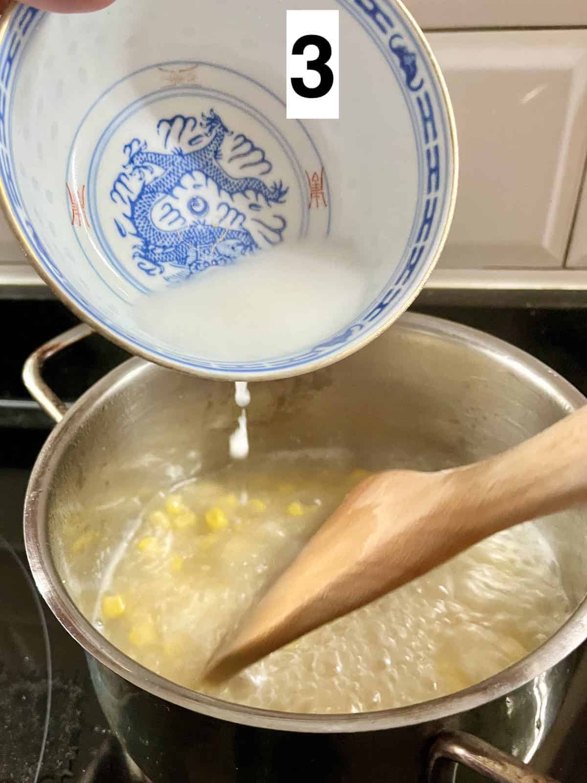 Adding cornstarch slurry to a pot of corn soup.