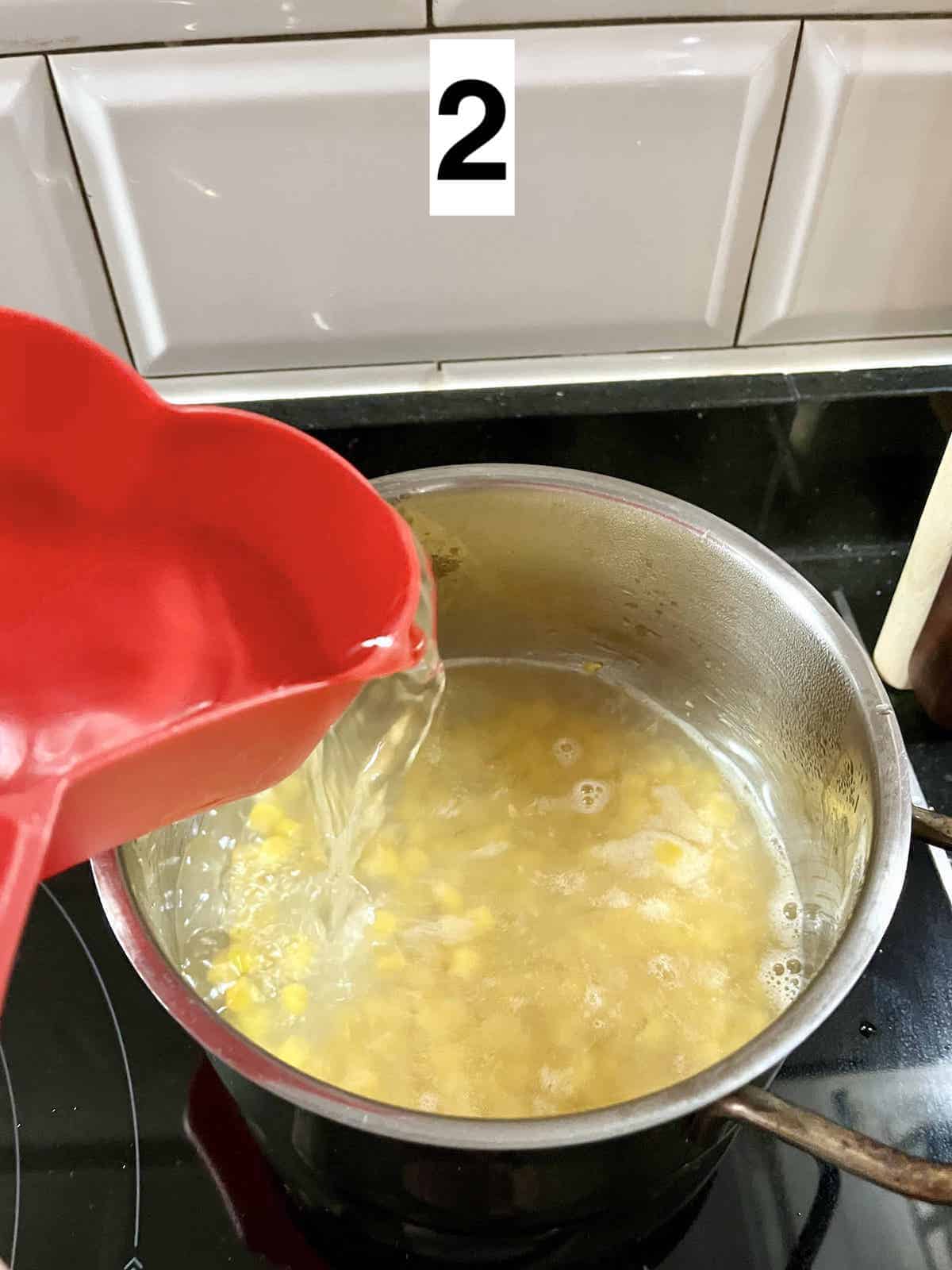 Adding chicken stock to a pot of corn.