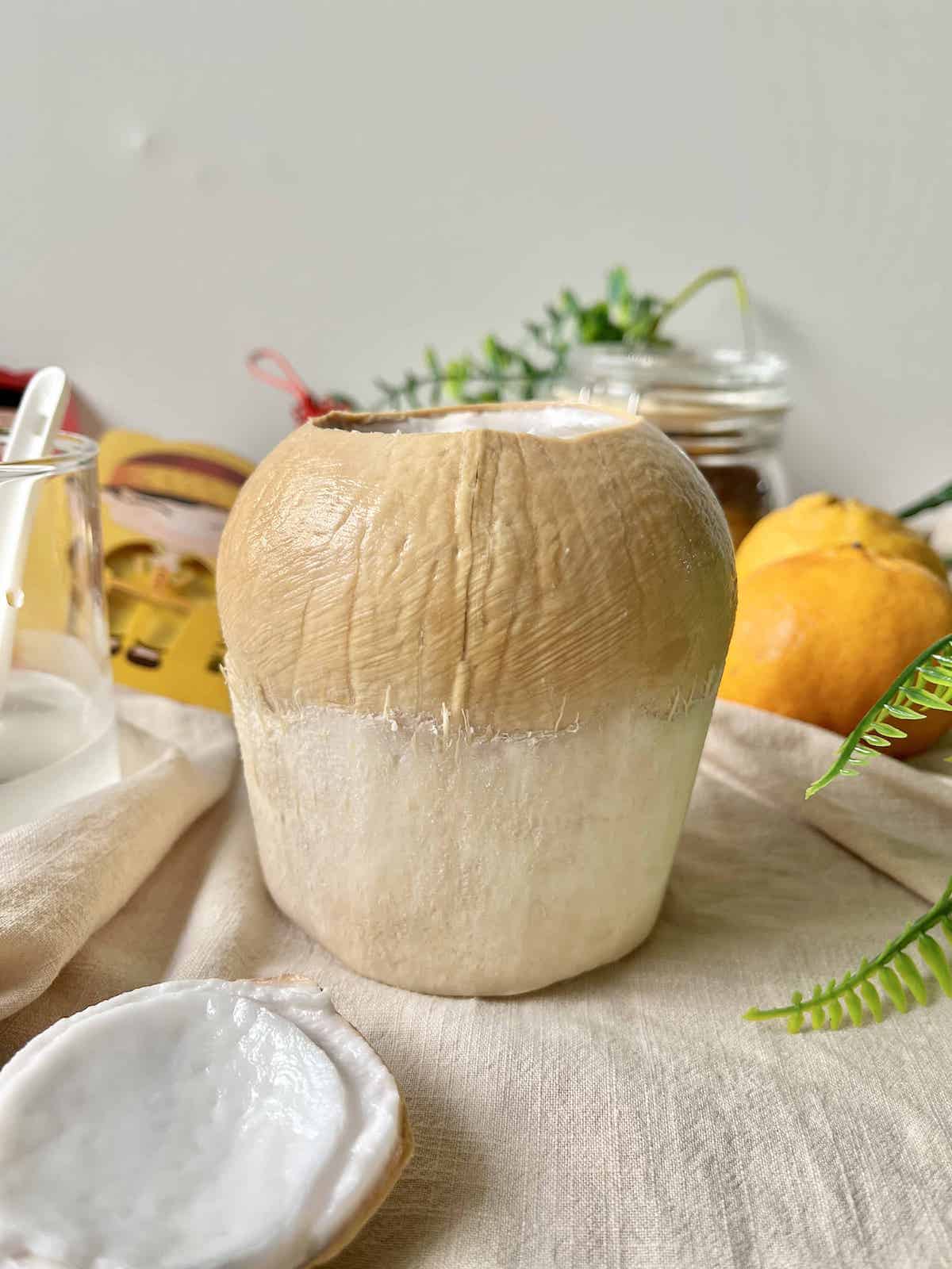 A fresh coconut with its top sliced off.