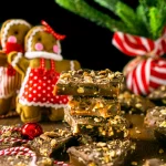 A pile of gingerbread toffee with 2 gingermen cookies in the background