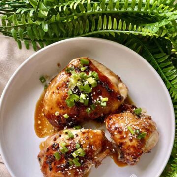 3 chicken thighs baked in teriyaki sauce with sesame seeds and green onions.