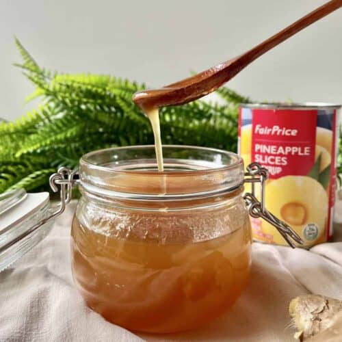 Scooping up some pineapple ginger syrup out of a glass jar.