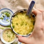 Holding up a bowl of egg drop soup with corn.