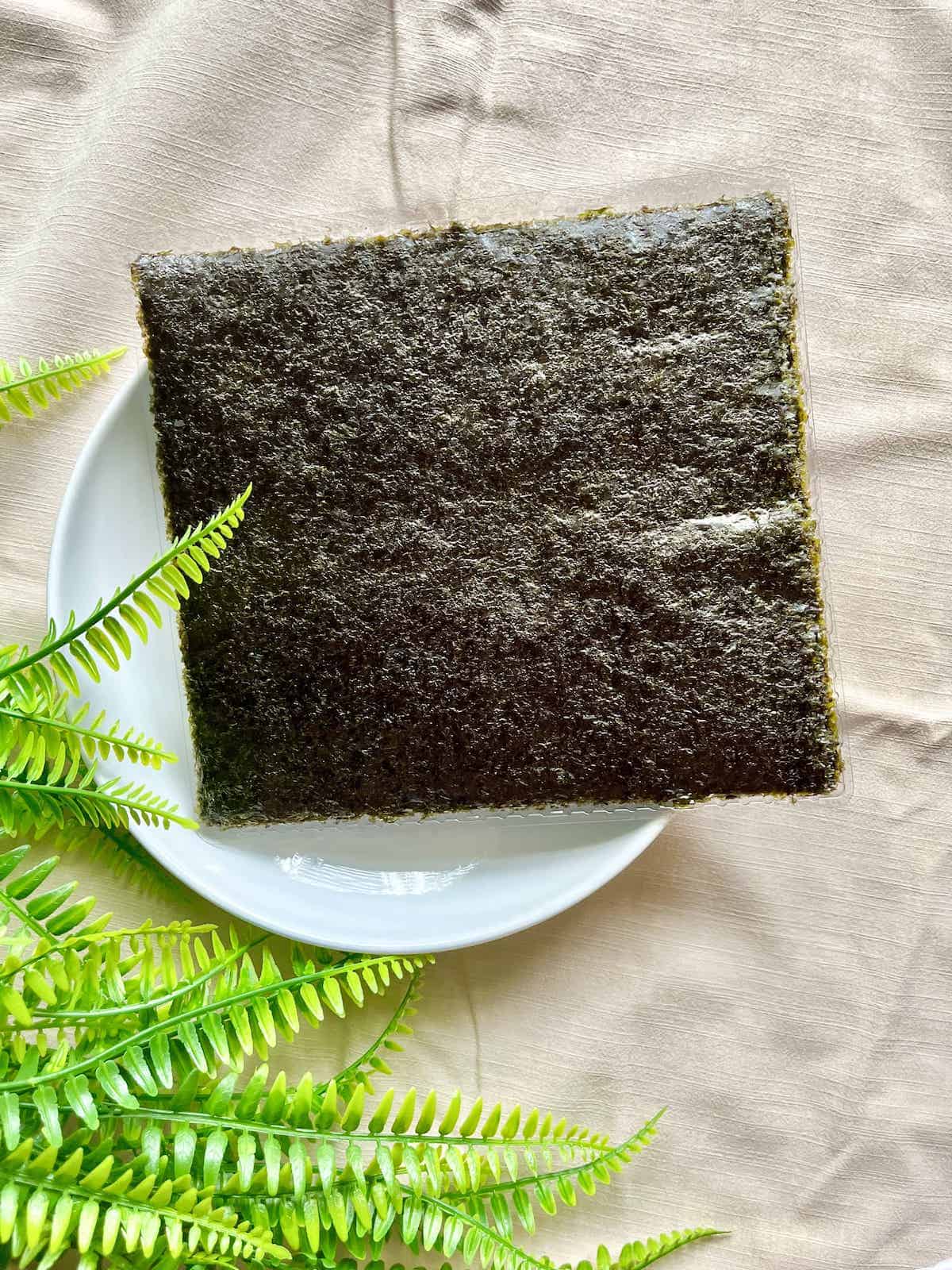 A stack of edible Japanese seaweed on a white plate.