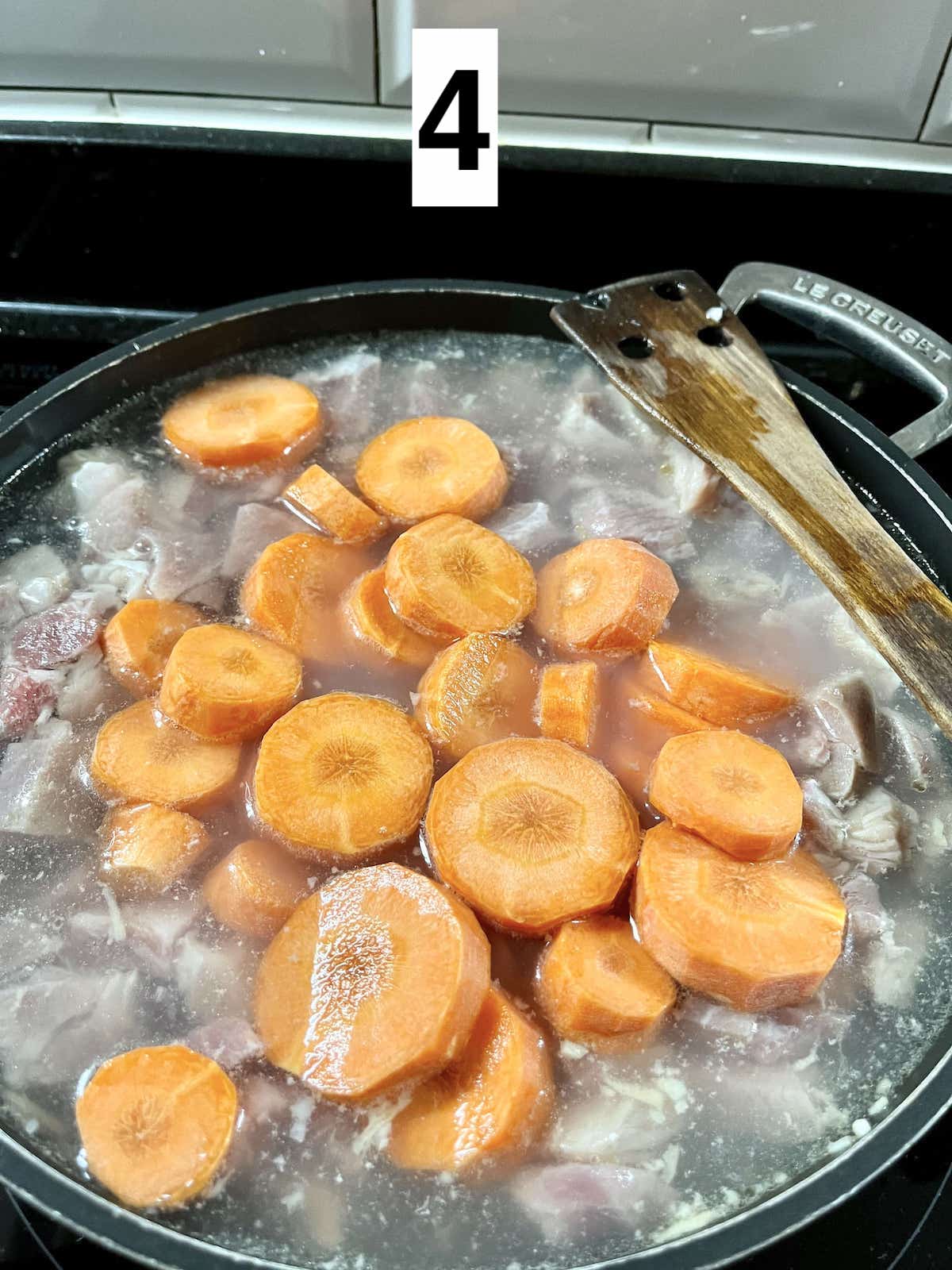 Boiling carrots and bite-sized pork pieces.