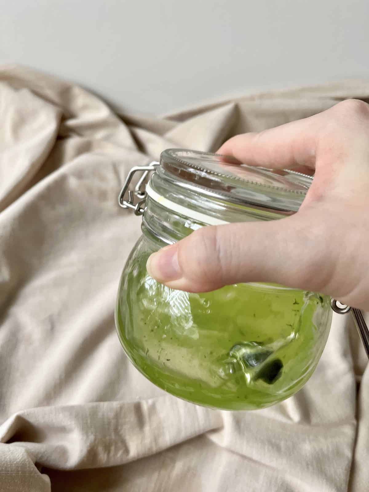 Shaking a tightly closed glass jar full of water and matcha powder.