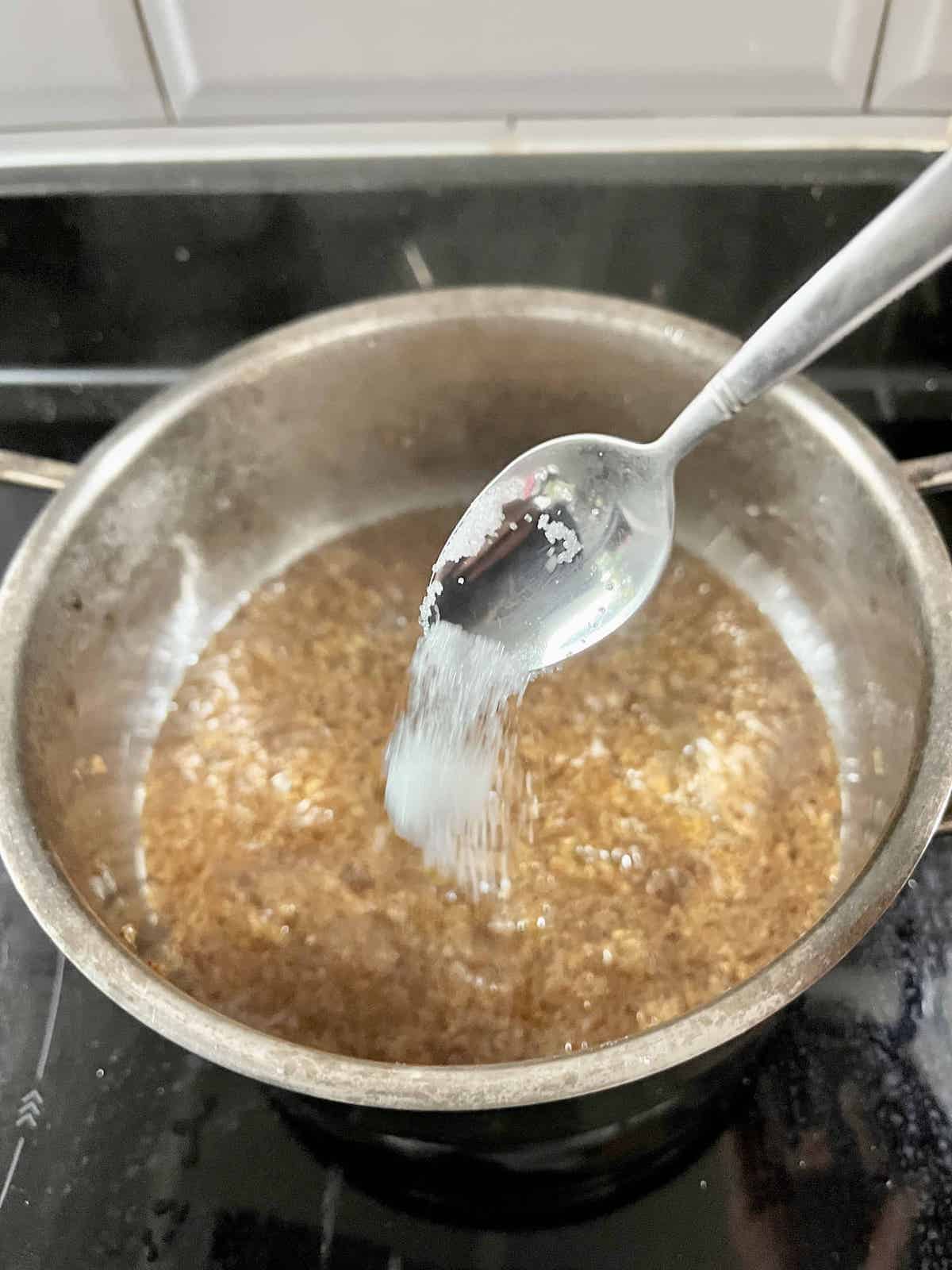 Adding sugar to a pot of hot osmanthus tea.