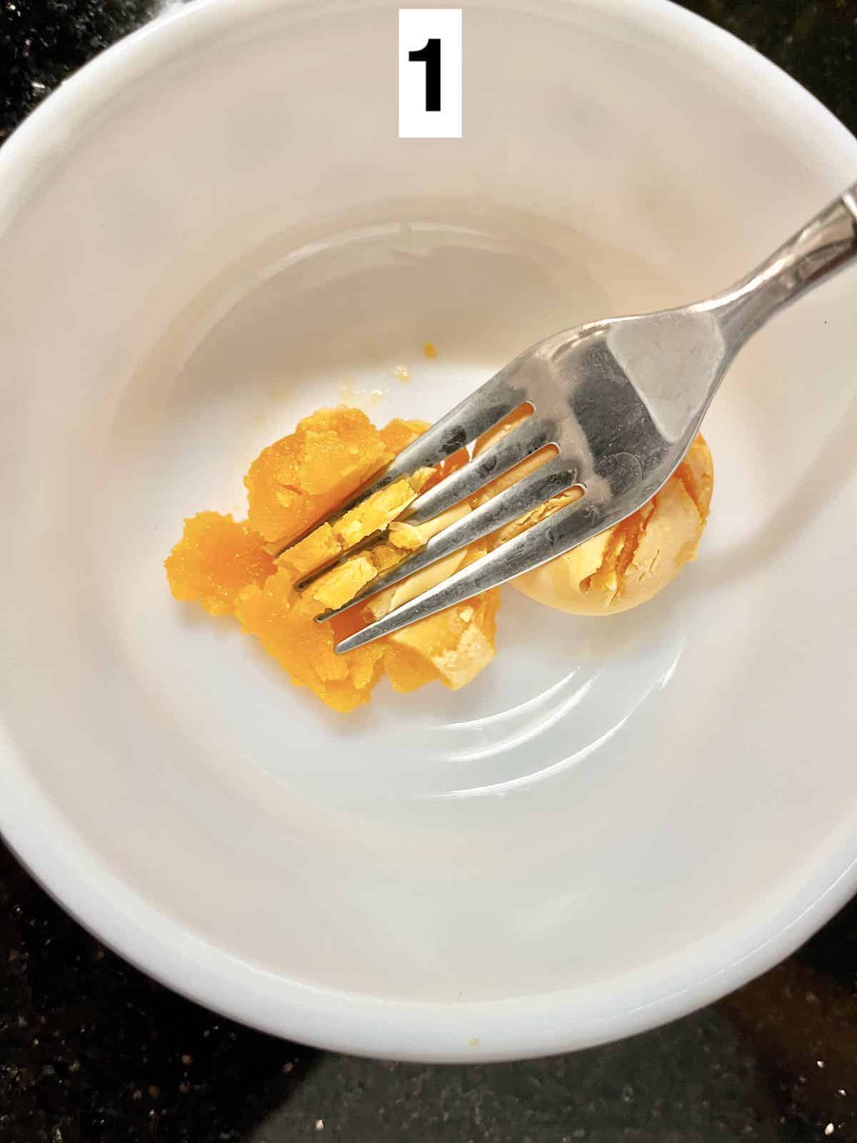 Mashing a cooked salted ducks eggs into fine crumbs.