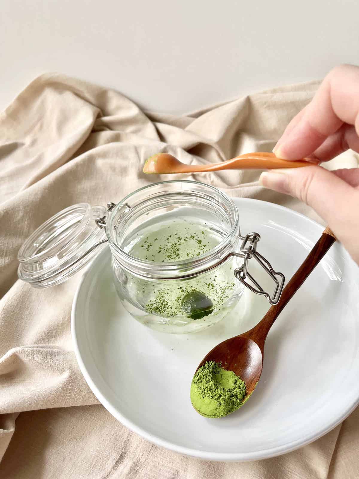 Adding matcha powder to water in a Mason Jar.