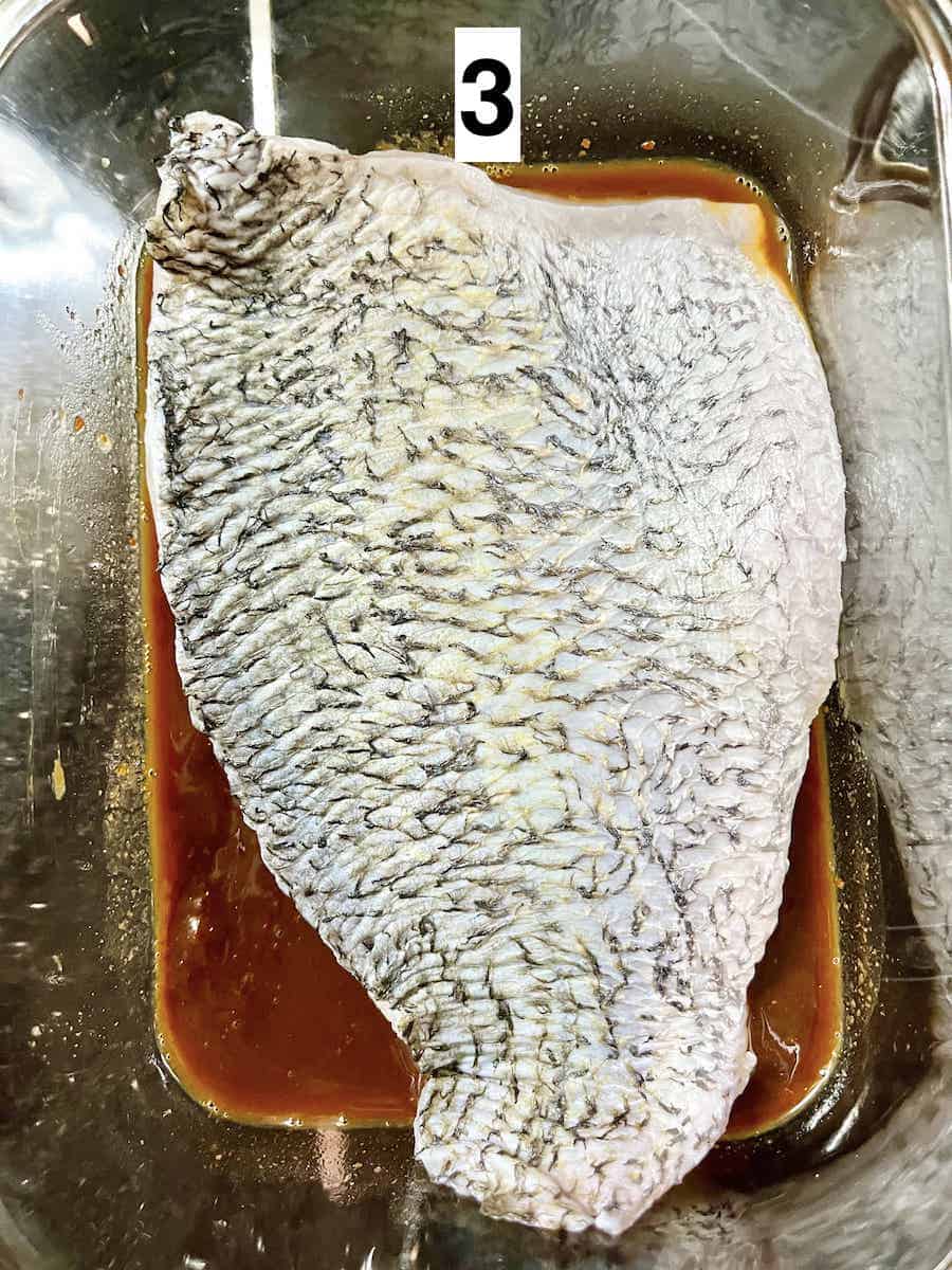 A piece of sea bass fillet sitting in miso marinade.