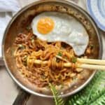 A pan of Korean gochujang noodles with spring onions and egg.