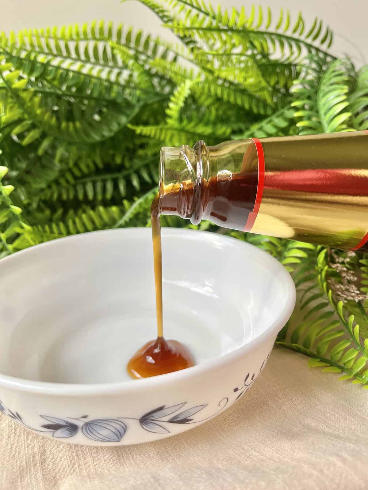 Pouring thick Chinese Oyster Sauce into a white bowl.