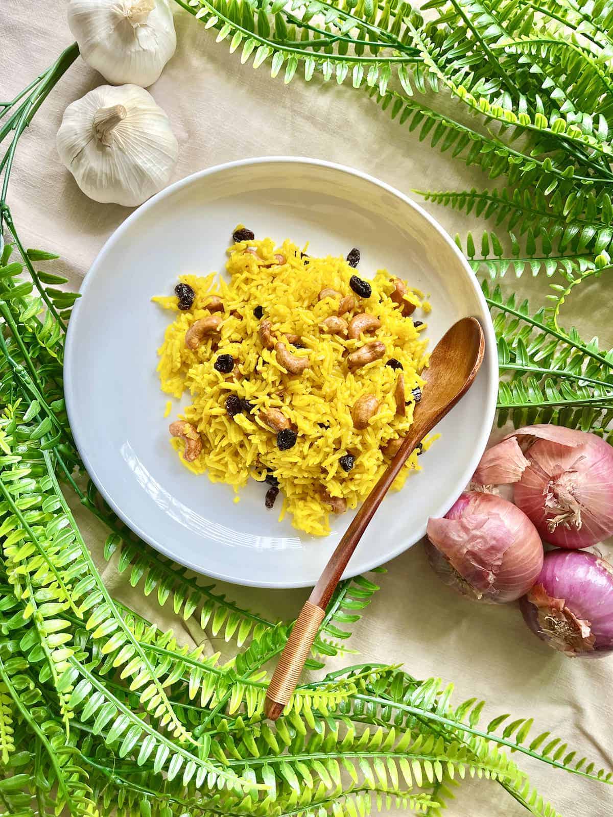 Golden turmeric rice with raisins and cashews on a white plate.