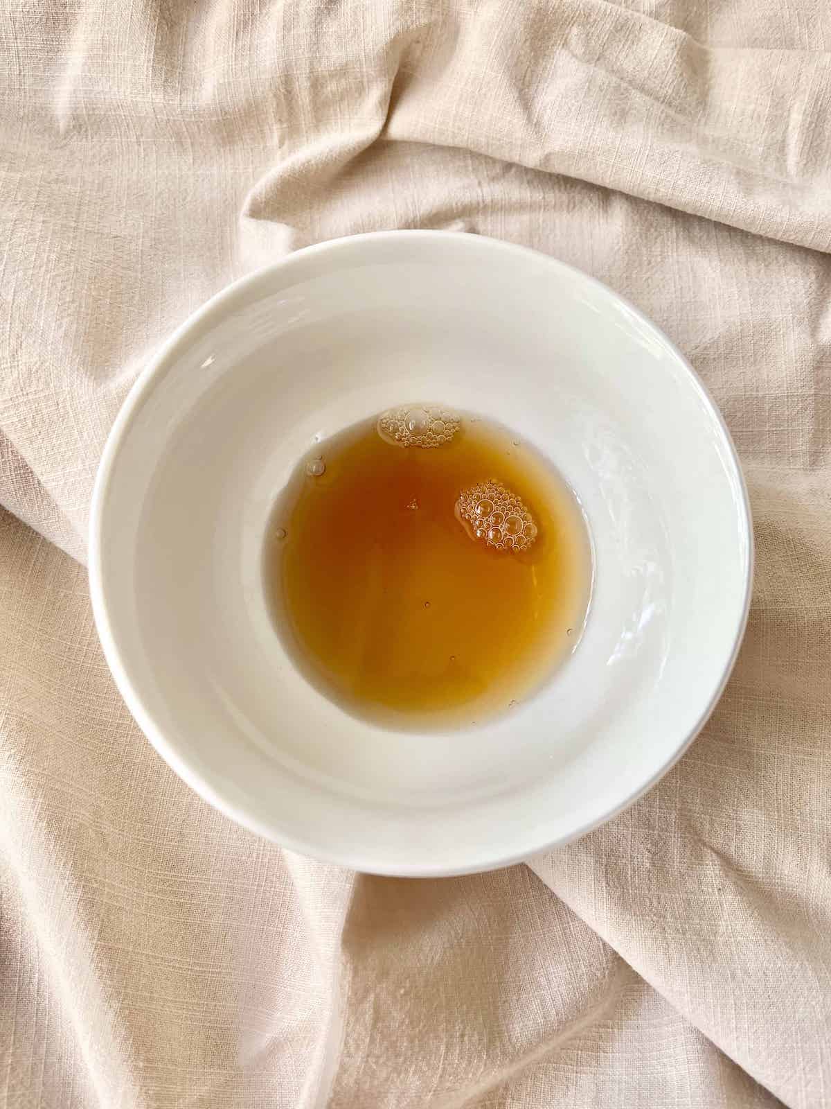 Overhead shot of brown coloured Shaoxing wine in a white bowl.