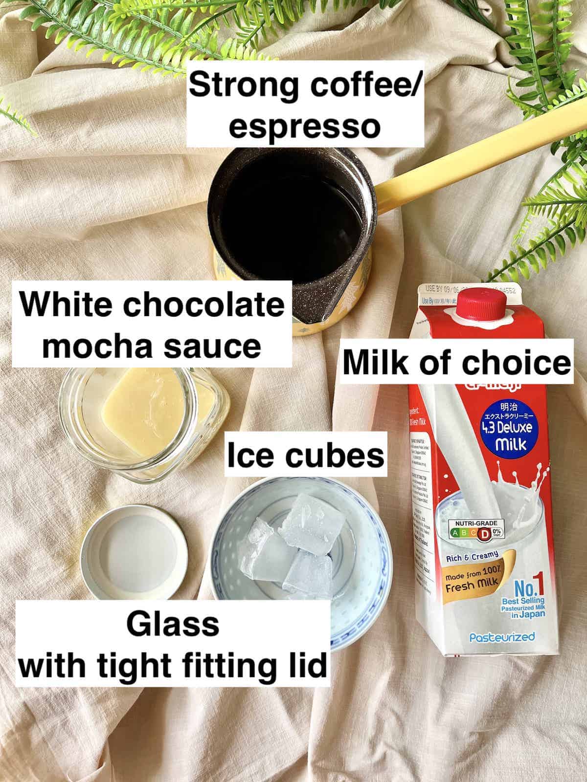 White chocolate sauce, ice, milk and coffee on a tablecloth.