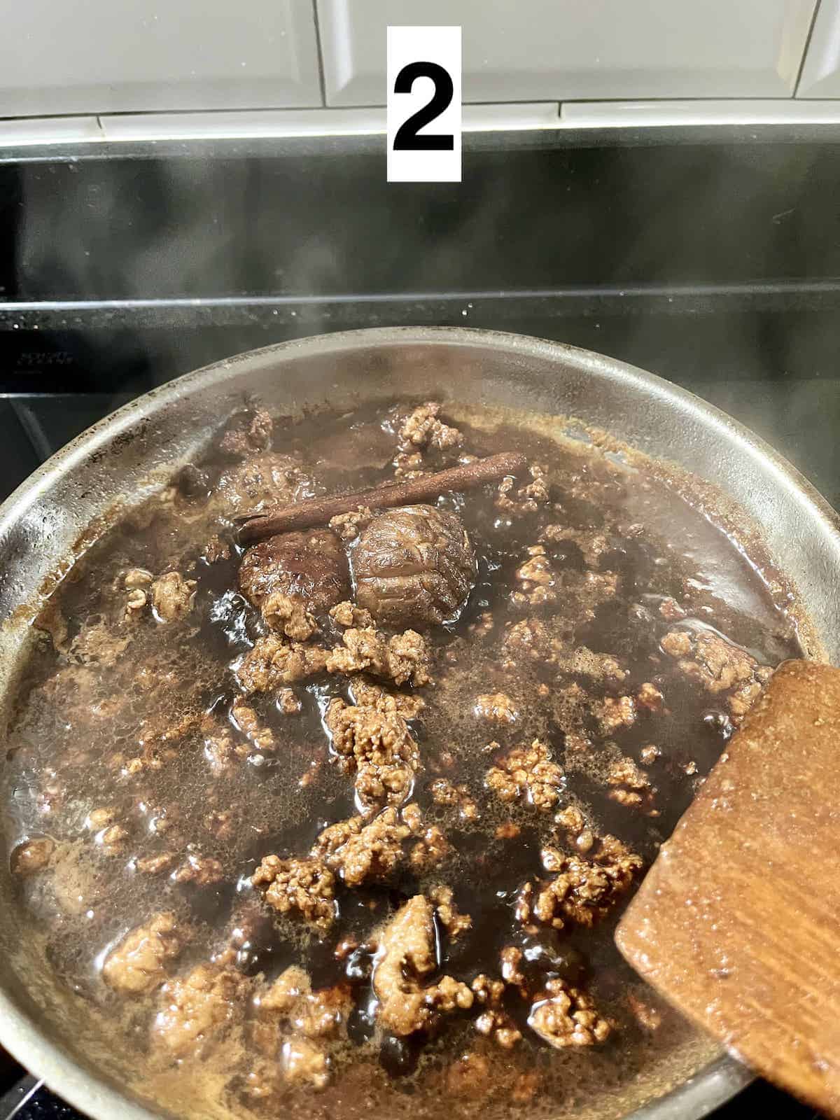 Simmering minced pork with a soy sauce mixture.