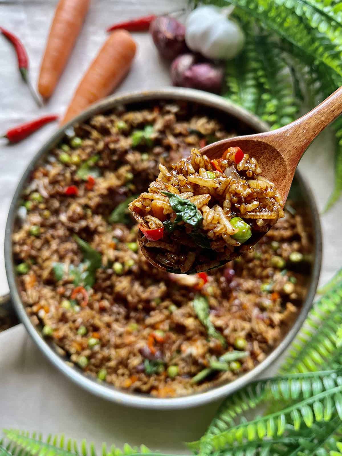 Scooping up some dark Thai fried rice with basili, carrots and peas.