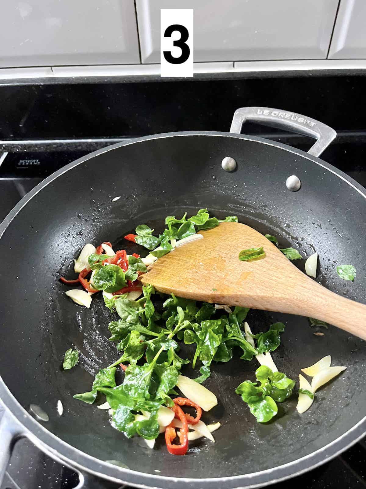 Stir-frying Brazilian spinach with garlic and chili.