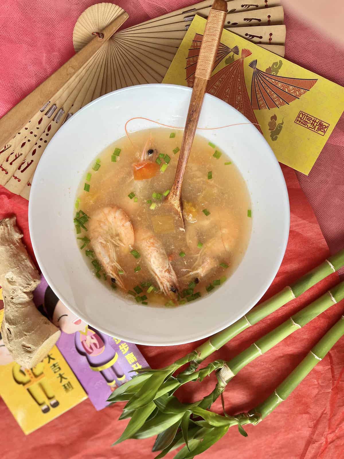 A bowl of Lemongrass soup with shrimp and green onions.