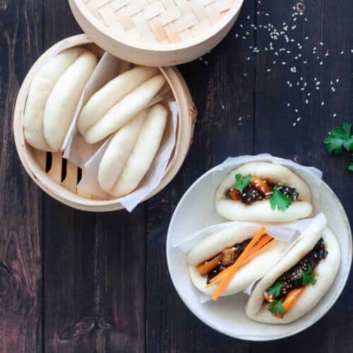 3 Bao Buns next to a bamboo basket with 3 steamed buns.