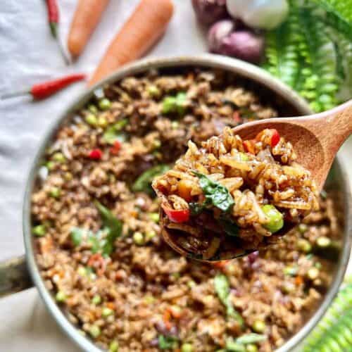 A spoonful of vegetarian Thai fried rice with Thai basil, peas, carrots and chilies.
