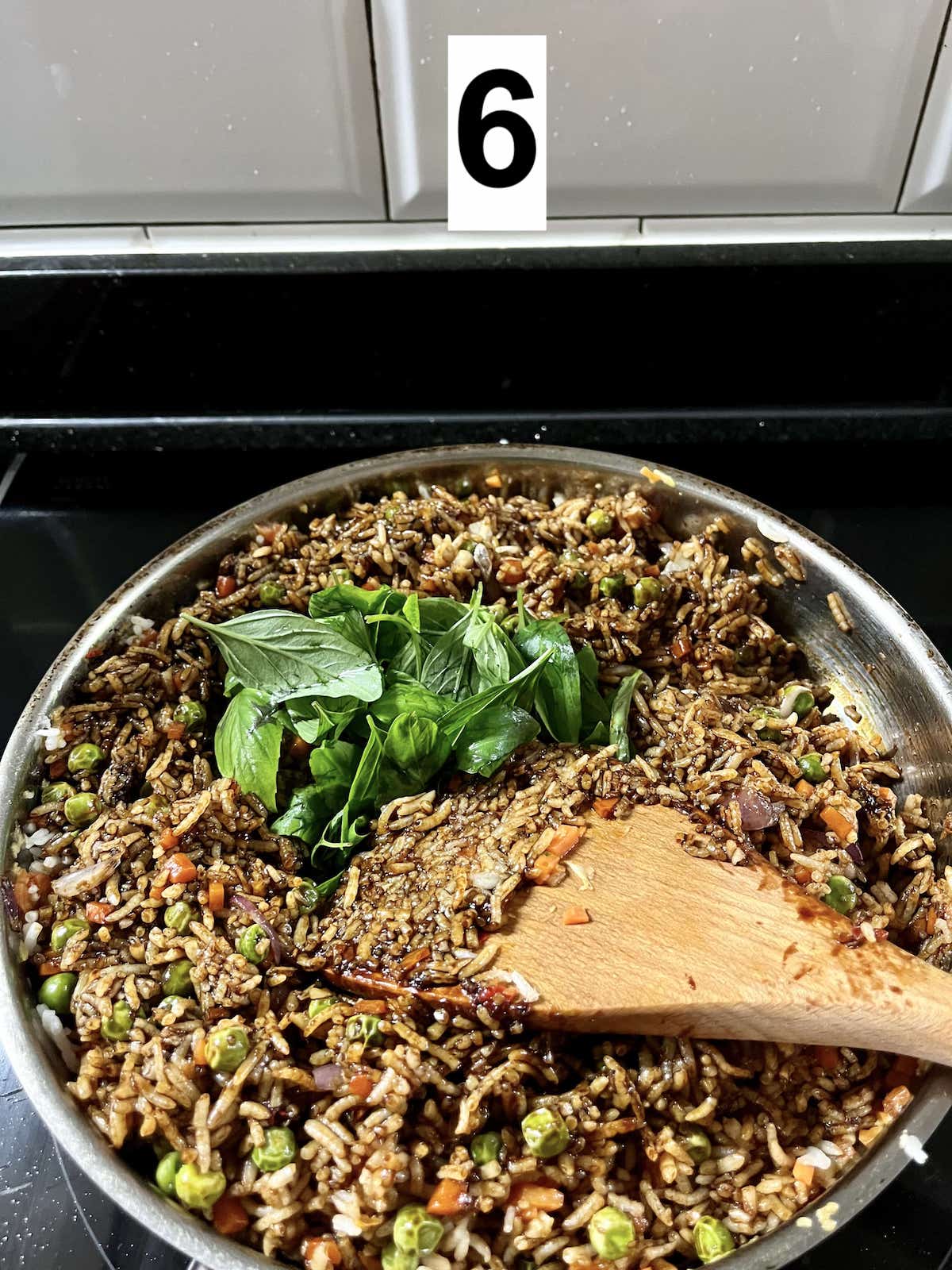 Stirring Thai basil leaves into fried rice.