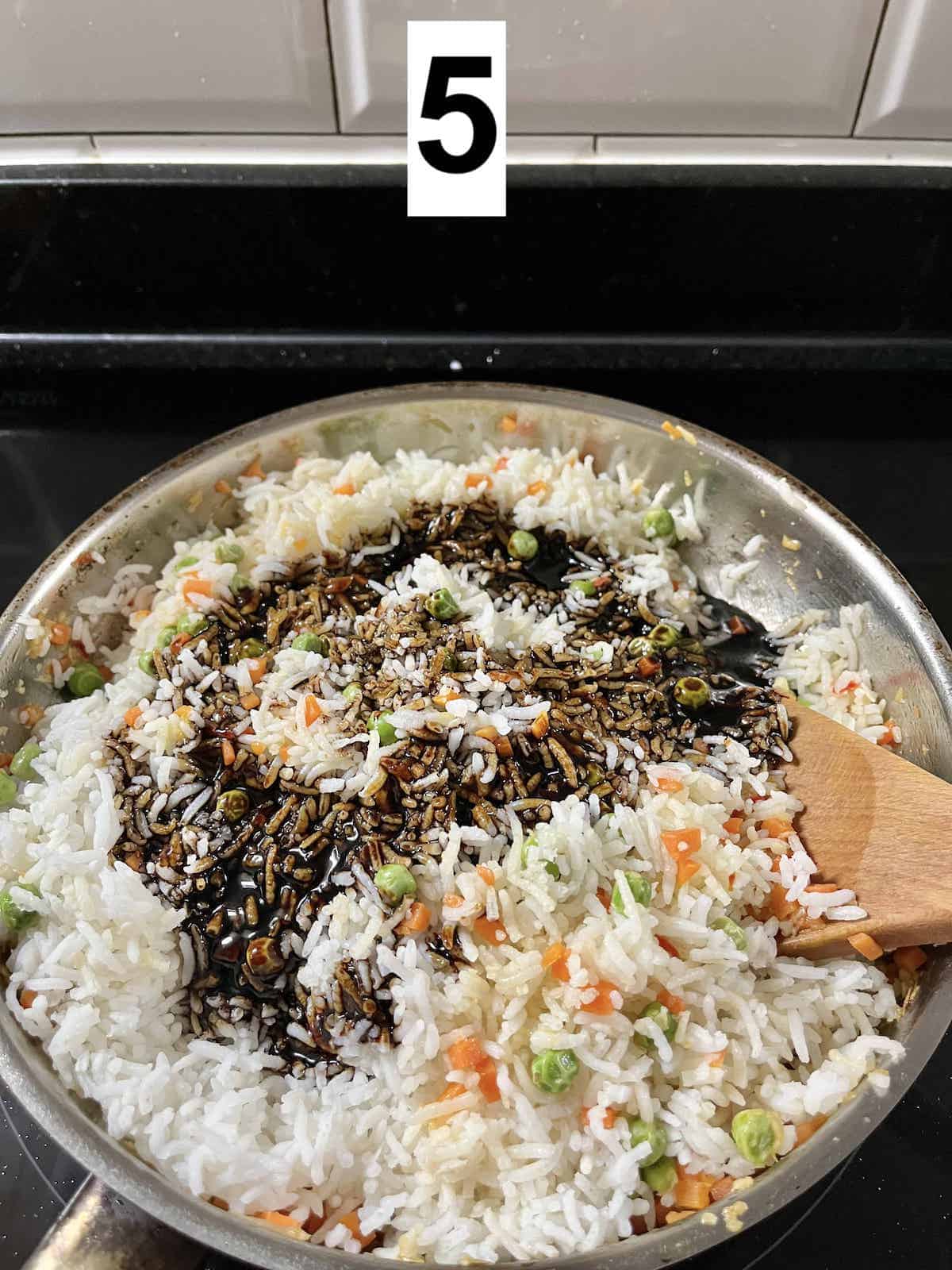 A pan full of white rice with a dark soy sauce mixture on it.