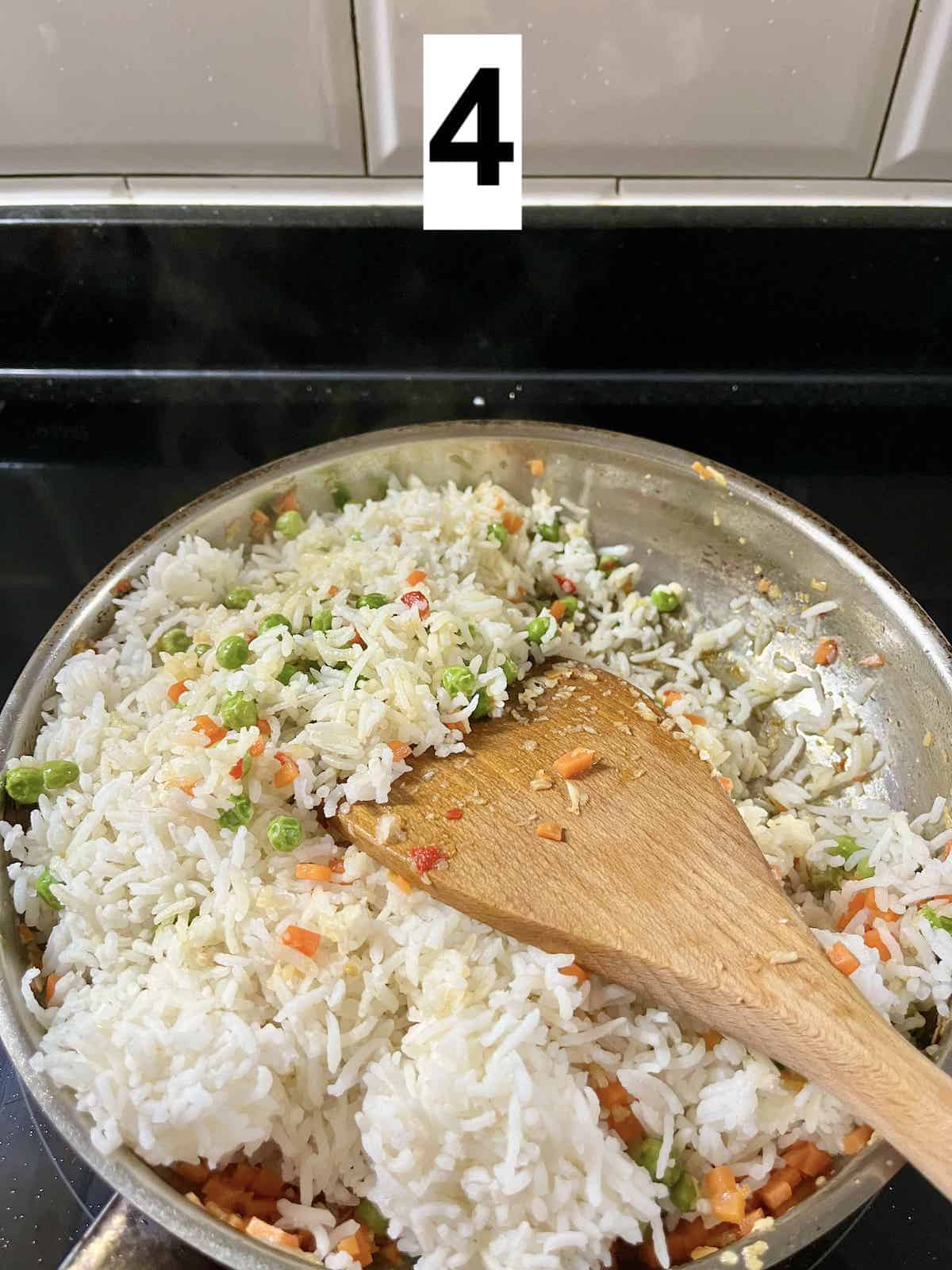 A pan full of rice with some peas and carrots.