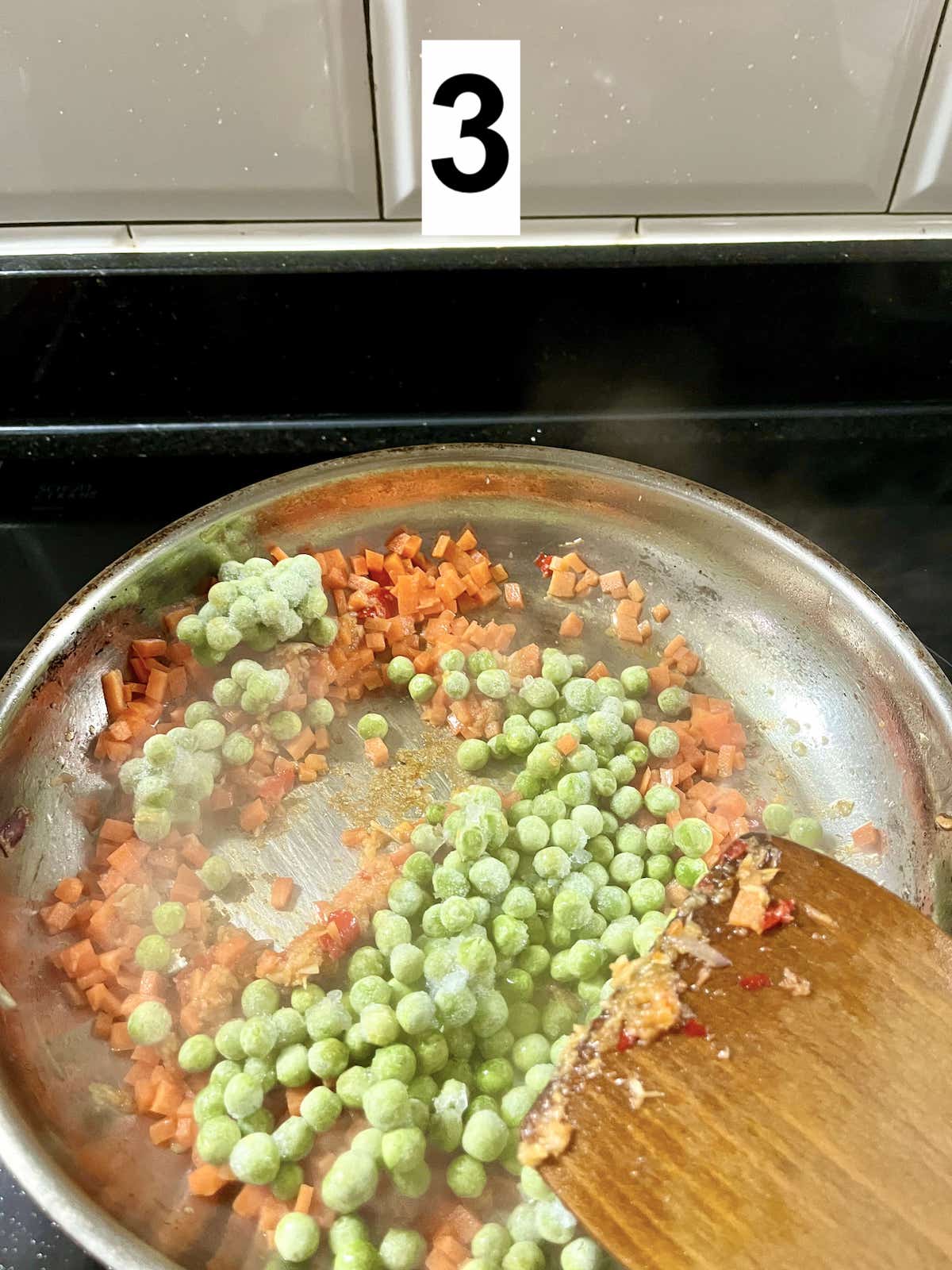 Stir-frying carrots and peas in a pan.