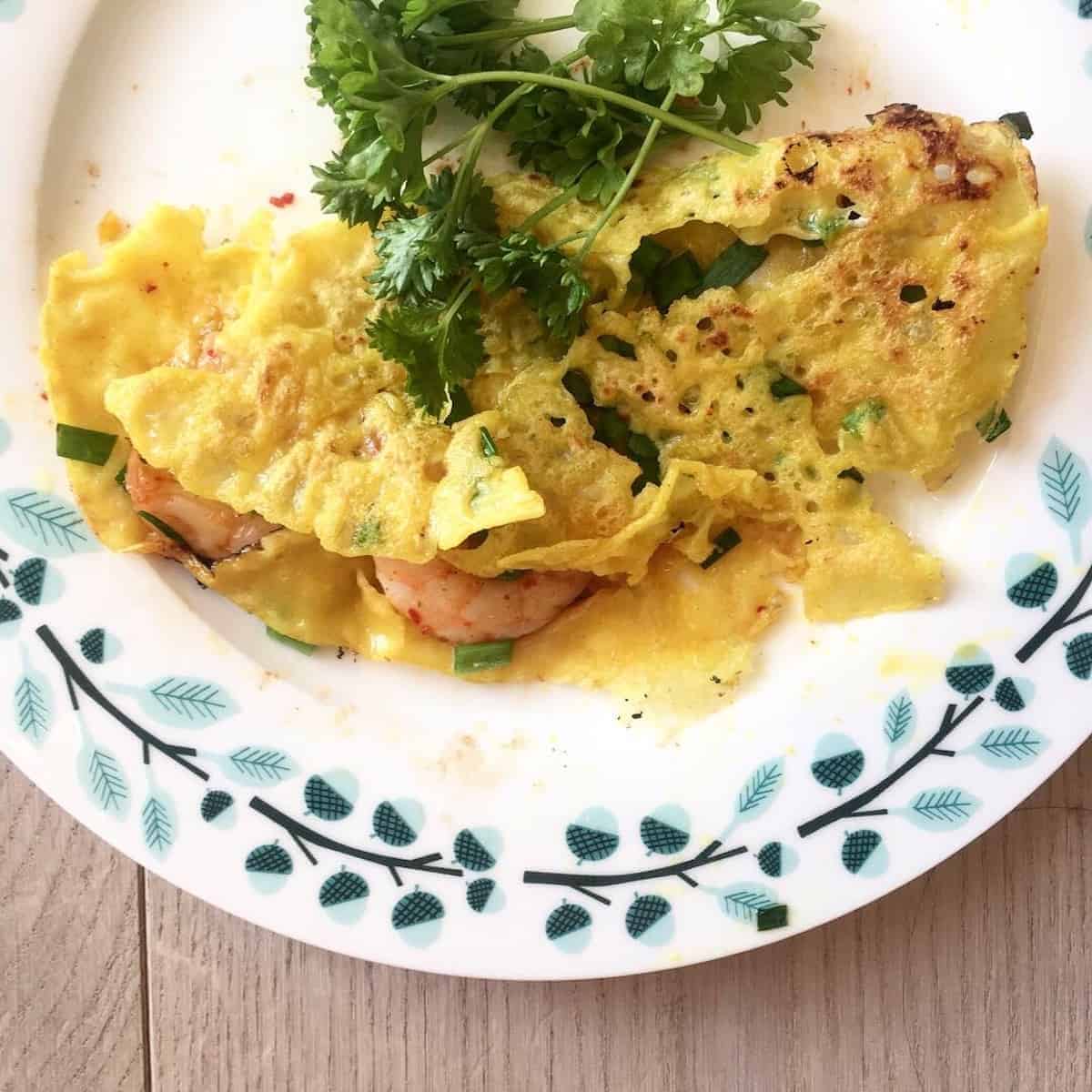 Vietnamese banh xeo with fresh herbs on a plate.