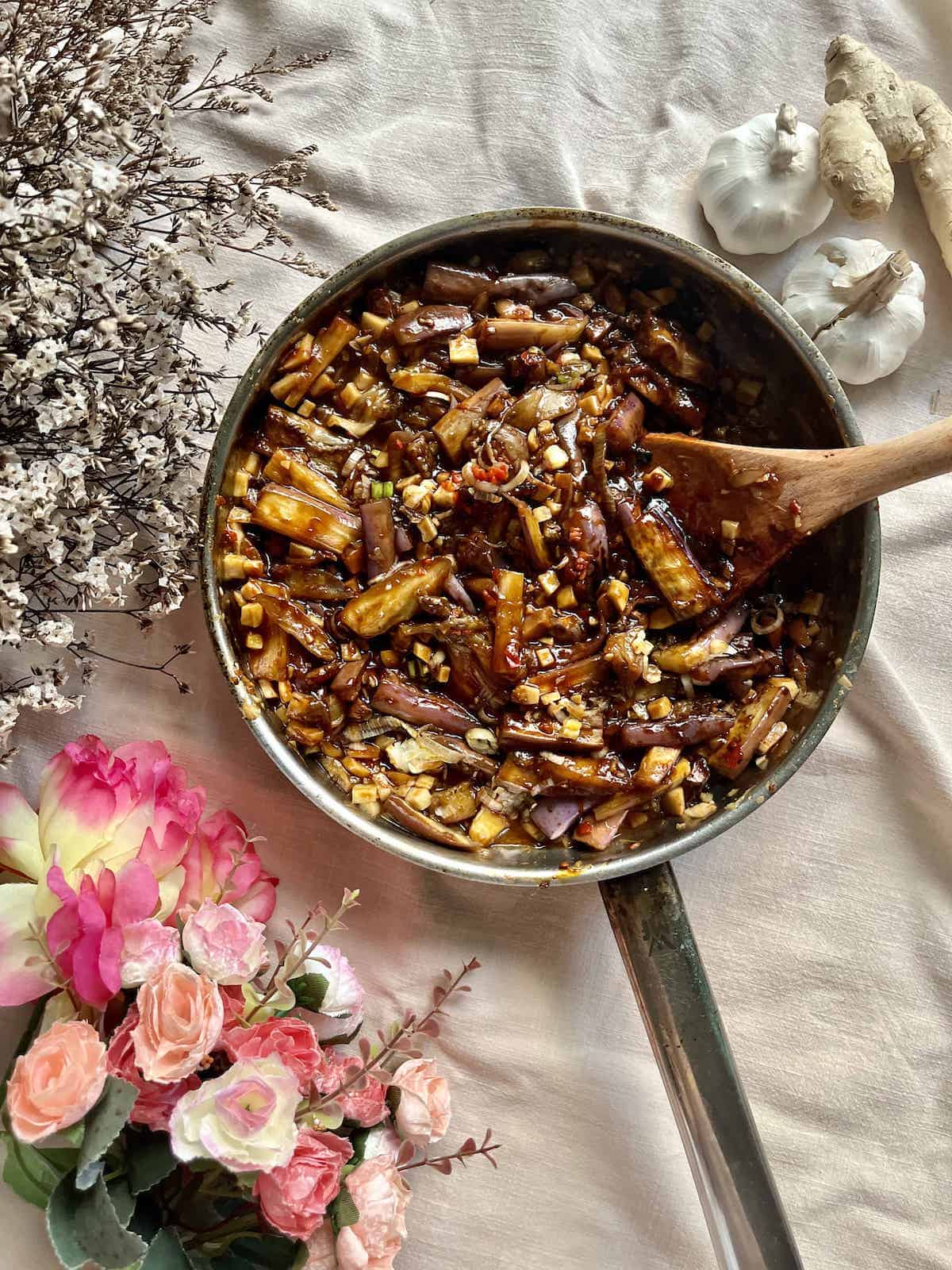 A pan full of Chinese sauteed eggplants with mushrooms, spring onions and chilies.