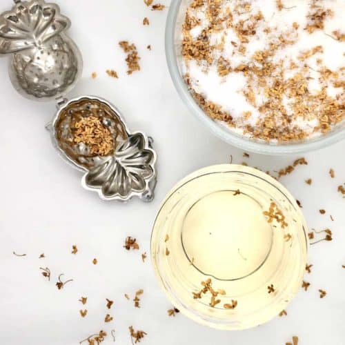 A cup of golden osmanthus tea made using dried gui hua flowers in a tea strainer