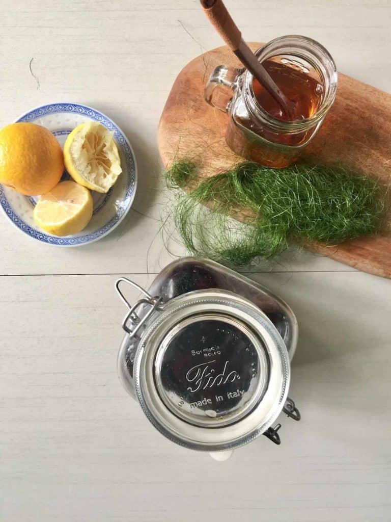 A glass of Korean plum tea with a squeezed lemon and maesil-cheong next to it