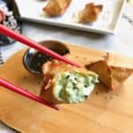 A red chopstick picking up a cream cheese wanton