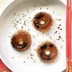 3 Chinese plum jellies with dried osmanthus flowers around them.